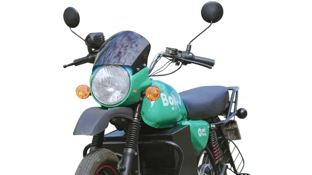 Young man smiling on a e-motorbike, parked next to highway, big city centre in the background